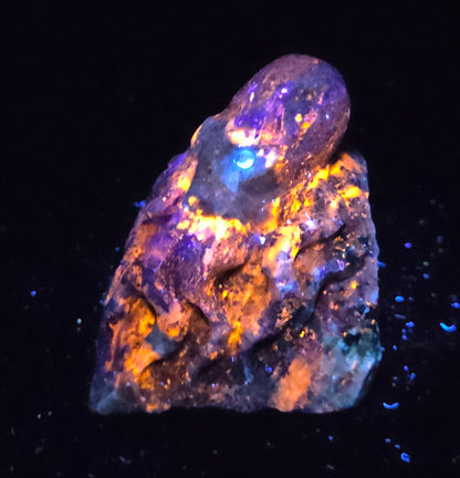 Blue crystal octopus carving with glowing orange under UV light against a marbled background