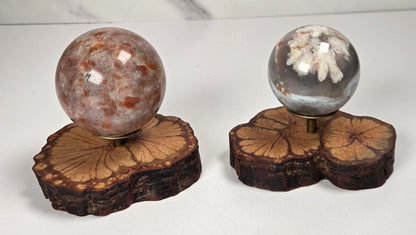 Wood slabs with bronze sphere holders with spherical carvings against a white background