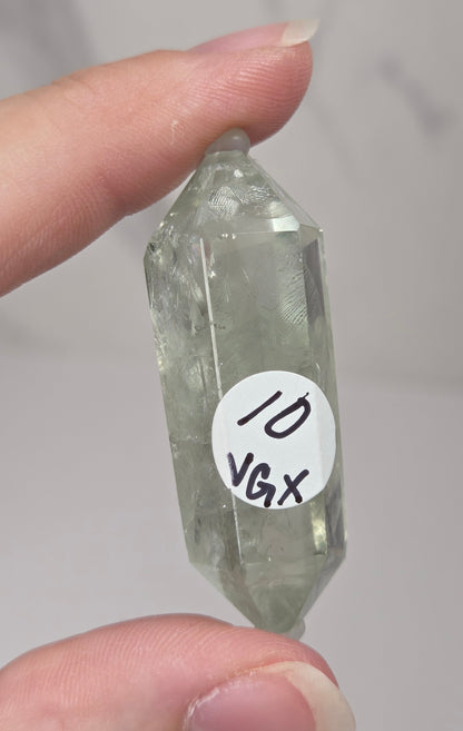 green quartz carved point being held in a hand against a white background