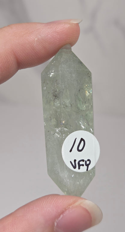 green quartz carved point being held in a hand against a white background