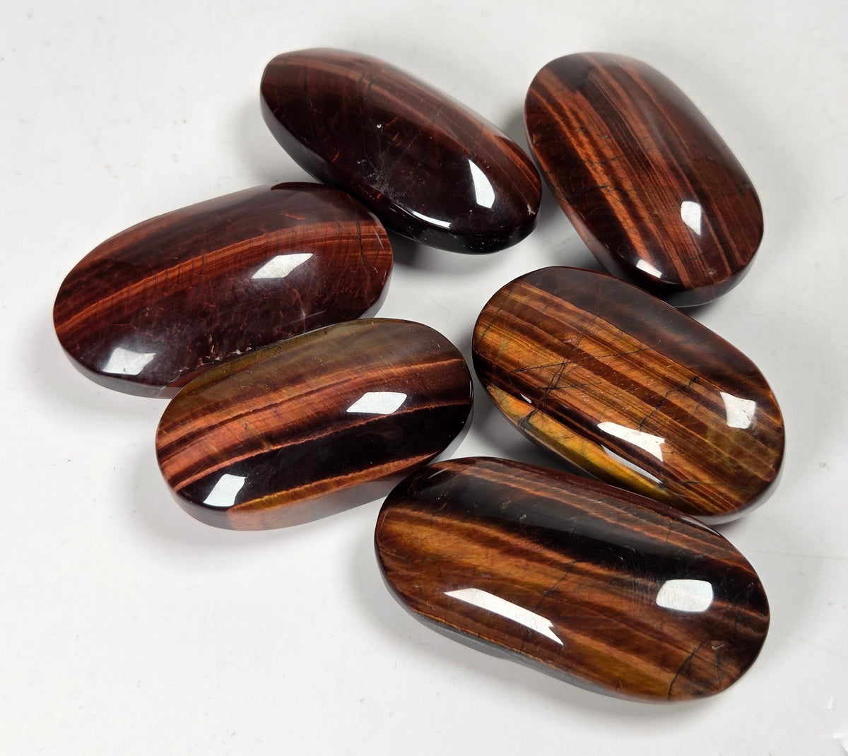 collection of red tigers eye crystal carvings with bands against a white background