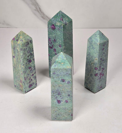 Green crystal polished points with pink and purple spots against a white background