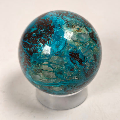 Blue and brown crystal polished sphere carving on an acrylic stand against a white background