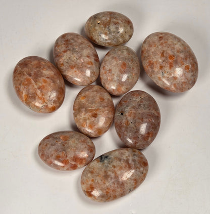 Collection of orange sunstone crystal polished carvings on a white background