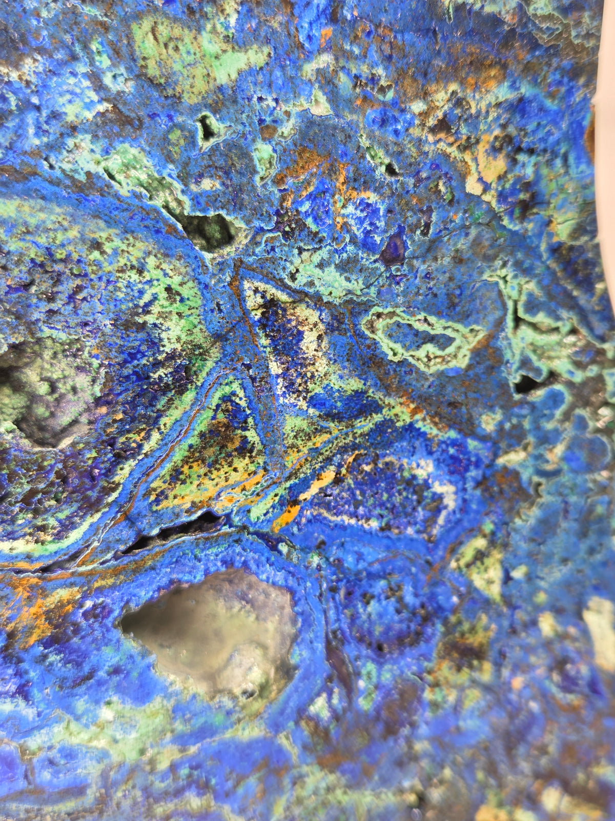 Close-up of a Crystal moon carving with green and blue coloring on a gold stand against a marbled background
