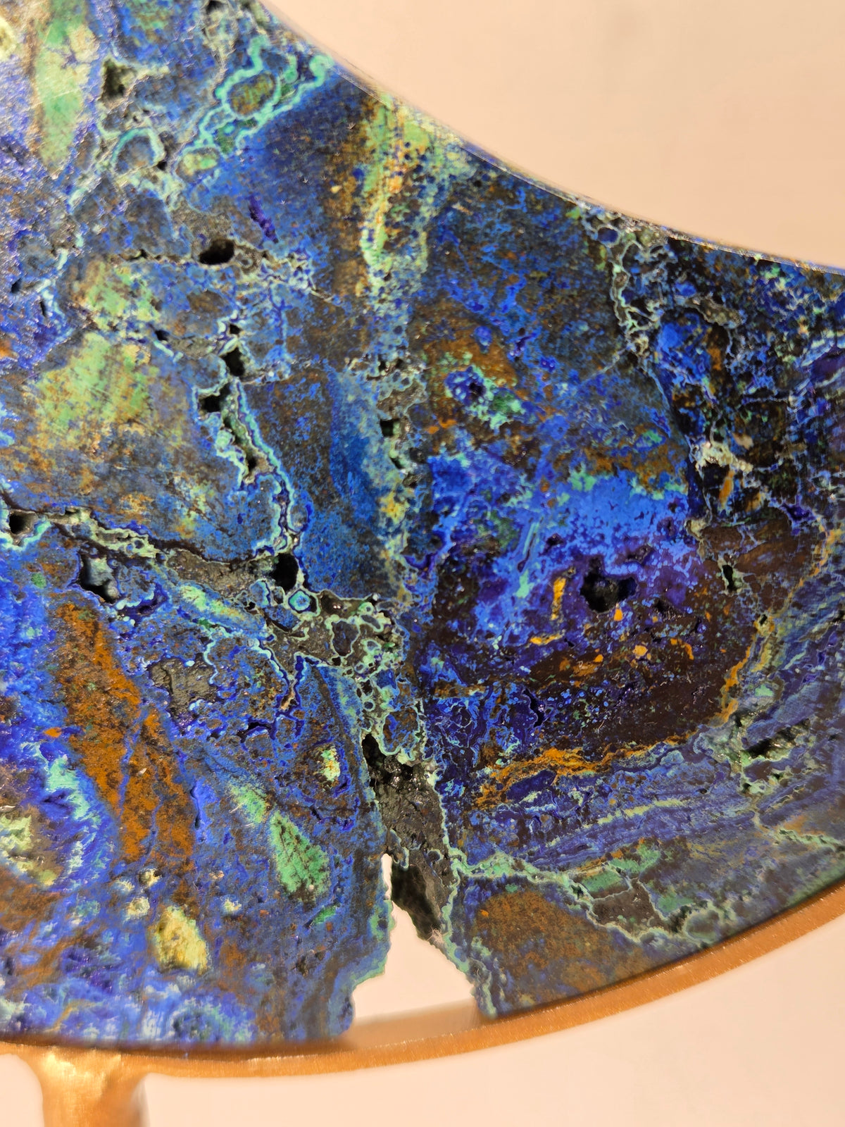 Close-up of a Crystal moon carving with green and blue coloring on a gold stand against a marbled background