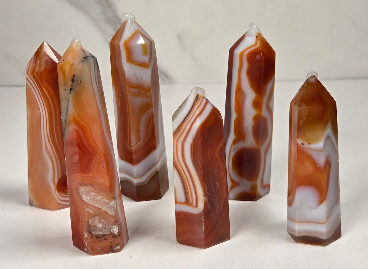 Polished carnelian crystal towers with beautiful white and red banding against a marbled background