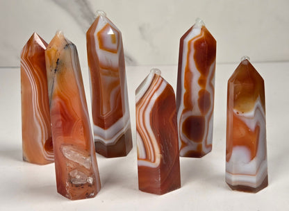 Polished carnelian crystal towers with beautiful white and red banding against a marbled background