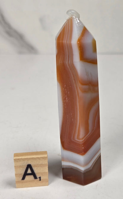 Polished carnelian crystal towers with beautiful white and red banding against a marbled background