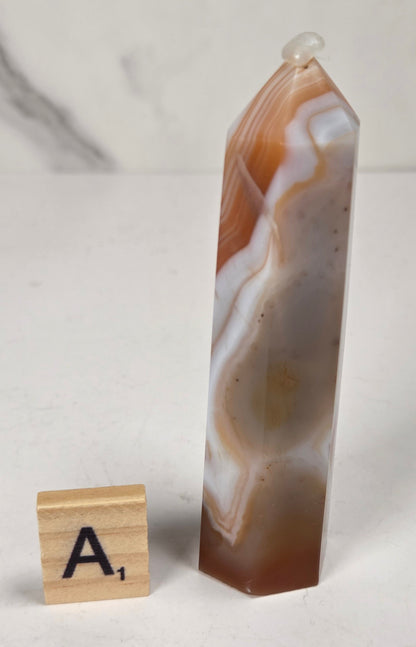 Polished carnelian crystal towers with beautiful white and red banding against a marbled background