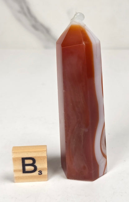 Polished carnelian crystal towers with beautiful white and red banding against a marbled background