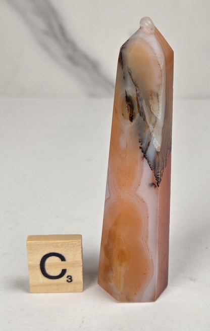 Polished carnelian crystal towers with beautiful white and red banding against a marbled background