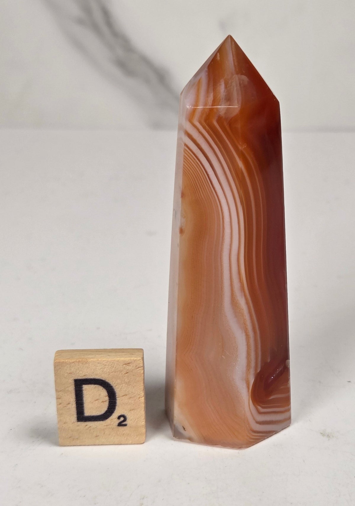 Polished carnelian crystal towers with beautiful white and red banding against a marbled background
