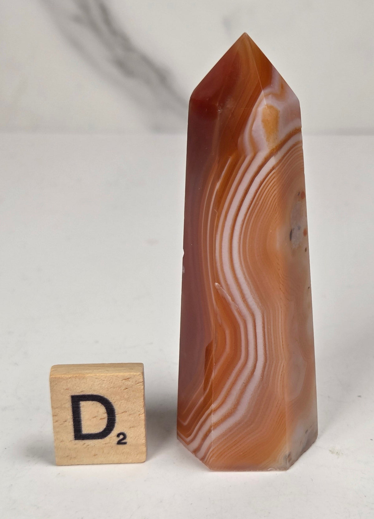 Polished carnelian crystal towers with beautiful white and red banding against a marbled background