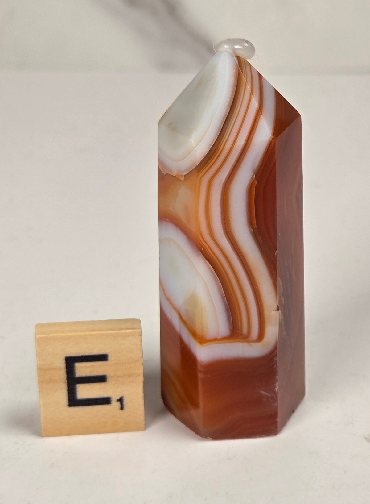 Polished carnelian crystal towers with beautiful white and red banding against a marbled background