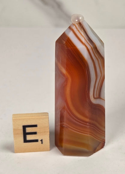 Polished carnelian crystal towers with beautiful white and red banding against a marbled background