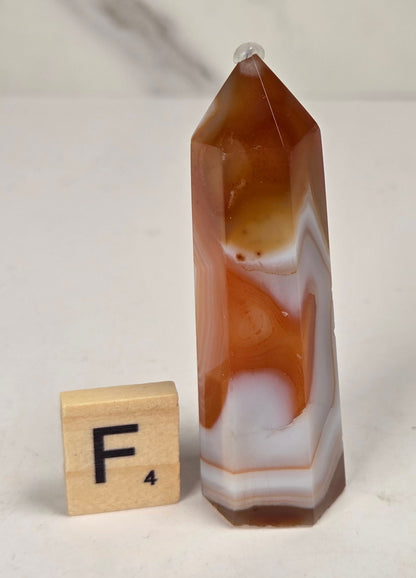 Polished carnelian crystal towers with beautiful white and red banding against a marbled background