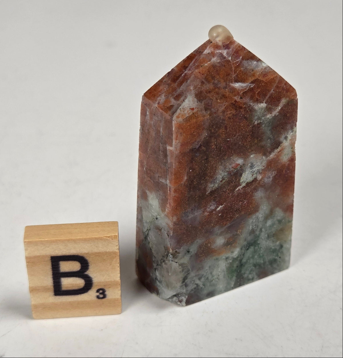 Orange crystal polished towers with white coloring with a scrabble tile against a white background