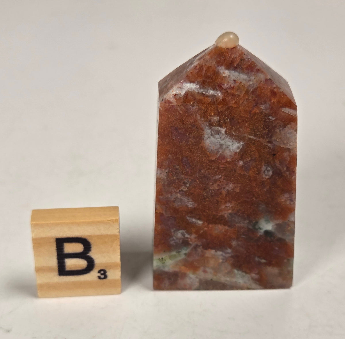 Orange crystal polished towers with white coloring with a scrabble tile against a white background