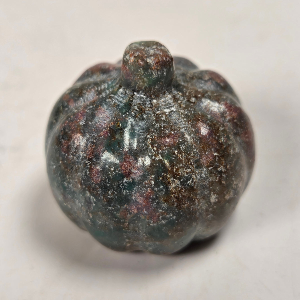 Polished crystal pumpkin carving with pink and grey coloring against a white background