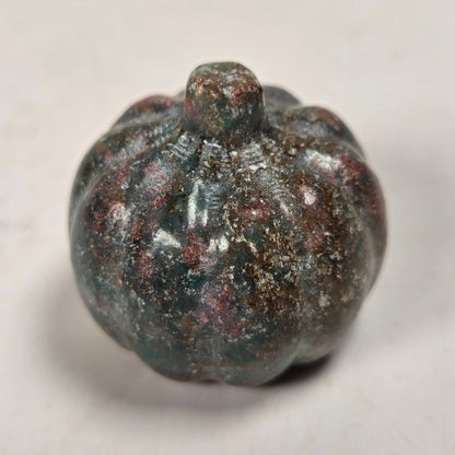 Polished crystal pumpkin carving with pink and grey coloring against a white background