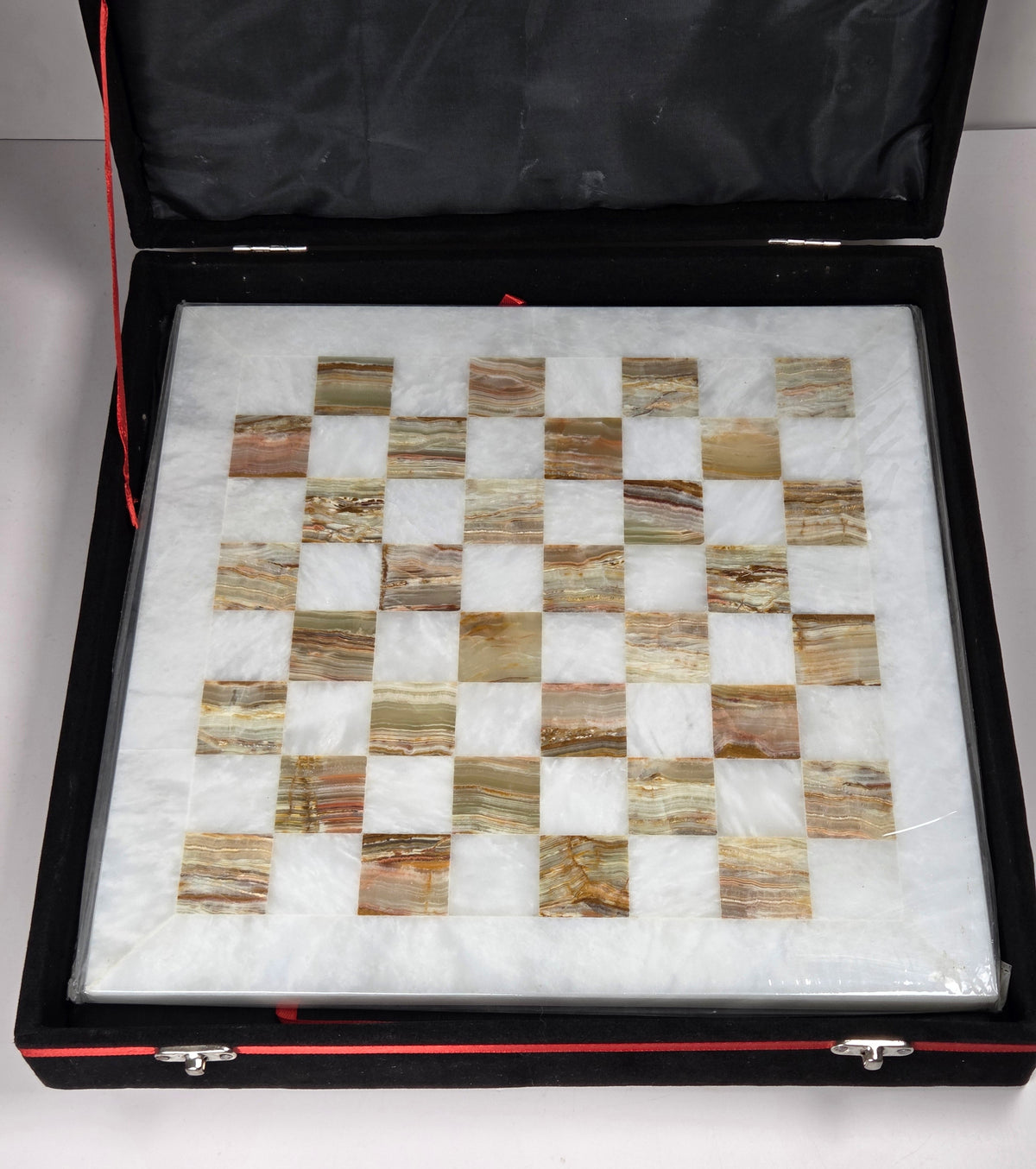 Crystal carved chess board in white and green color in a black case against a white background