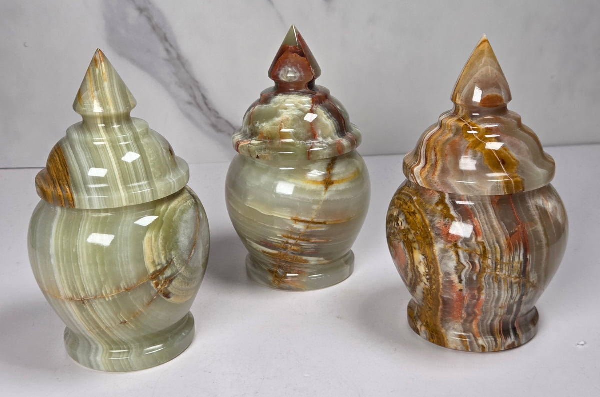 Set of 3 banded calcite candy jars with green, brown and red banding against a marbled background