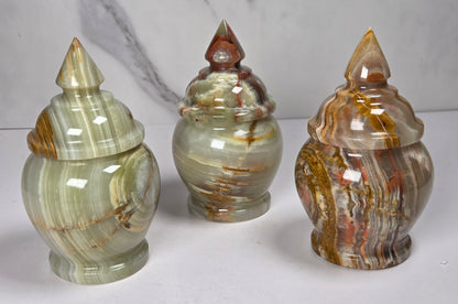 Set of 3 banded calcite candy jars with green, brown and red banding against a marbled background