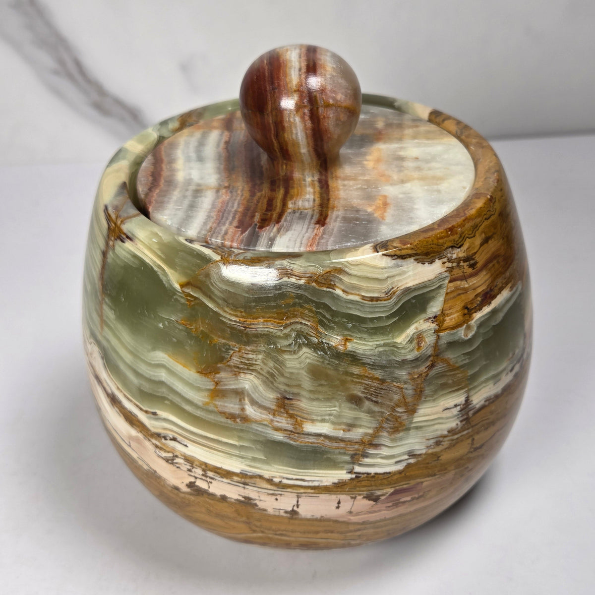 banded calcite jars with green, brown and red banding against a marbled background
