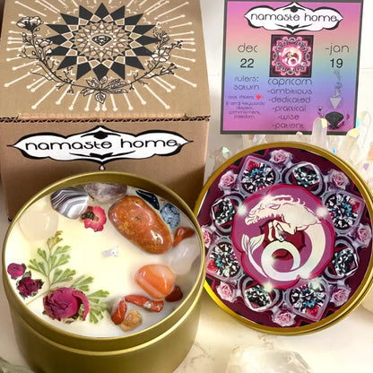 A Namaste Home wax melt gift set shown open, featuring a round gold tin with white wax, embedded crystals, dried rose petals, and botanical illustrations, alongside its decorated kraft box and a pink and purple astrology-themed card.