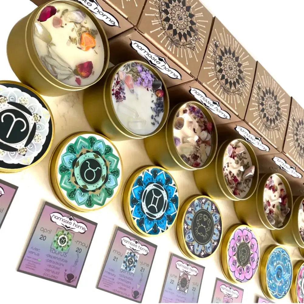 A collection of handcrafted candles in round tins with colorful mandala-patterned lids, alongside decorative kraft gift boxes, all arranged on a light beige surface.