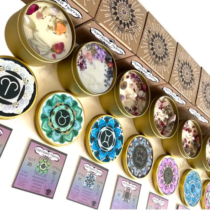 A collection of handcrafted candles in round tins with colorful mandala-patterned lids, alongside decorative kraft gift boxes, all arranged on a light beige surface.