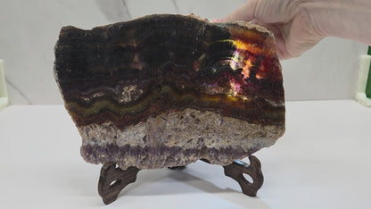 Banded crystal slices with multiple colors and inclusions on stands against a marble background, being backlit