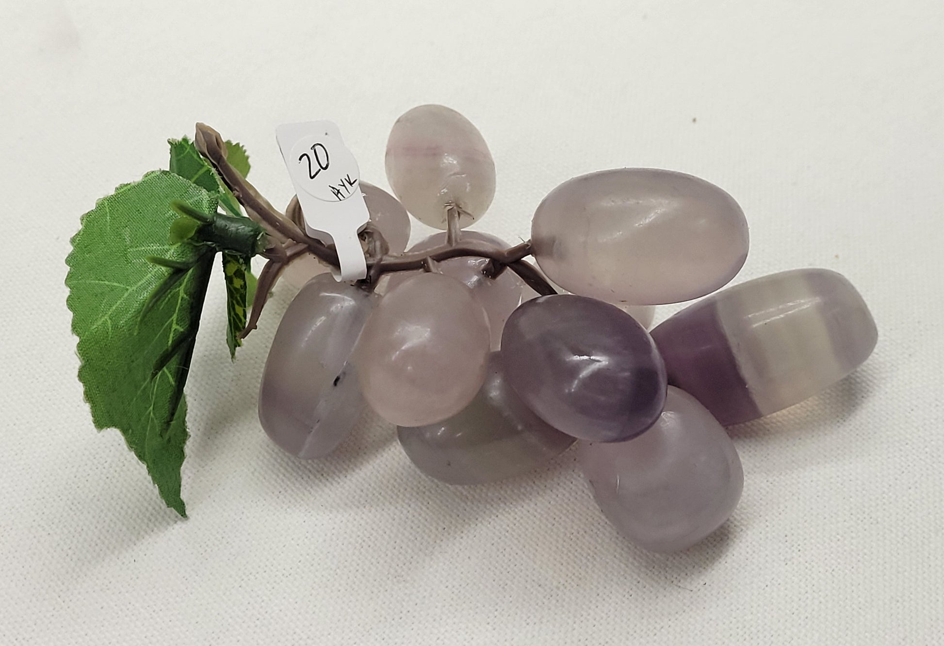 Purple Fluorite grape cluster carving on a white background